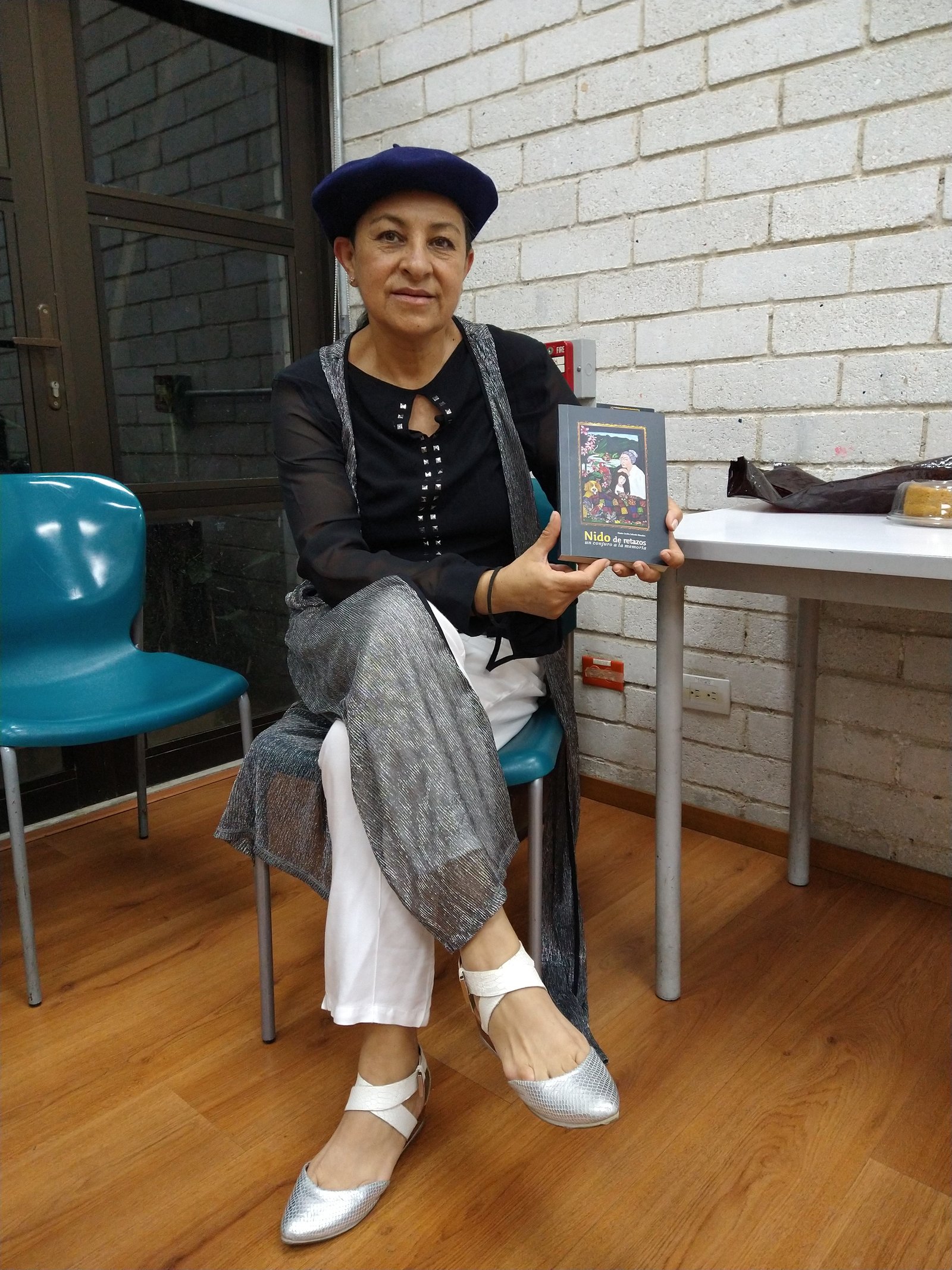 Marta (Mae) Salcedo exhibe con orgullo un ejemplar de su obra "Nido de retazos, un conjuro a la memoria". • Foto: Comunicando Belén.