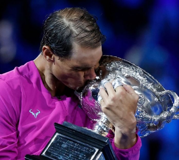 El tenista español Rafael Nadal besa el trofeo del Abierto de Australia 2022, su más reciente conquista. • Imagen: El País.